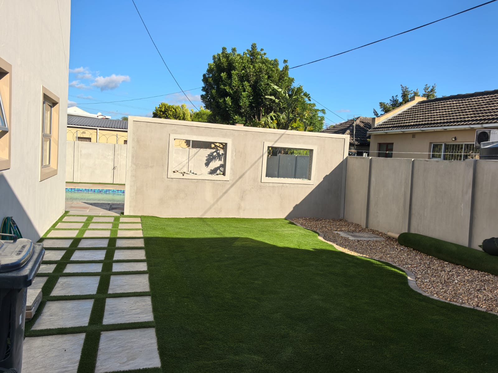 Landscaped yard with paving, turf and a plastered feature wall